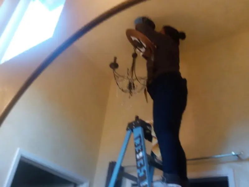Electrician installing a chandelier in a Bellevue residence